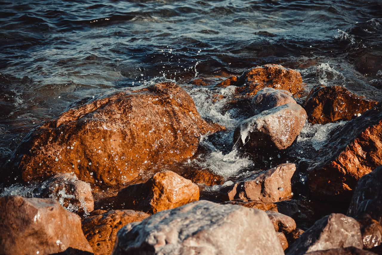 HIGH ANGLE VIEW OF ROCKS ON SEA SHORE