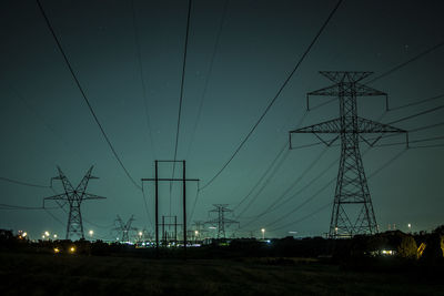 Low angle view of electricity pylon on field against sky