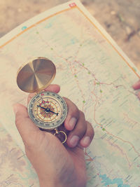 High angle view of person holding navigational compass over map