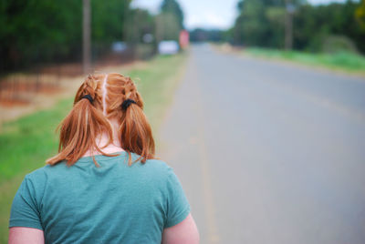Rear view of young woman standing on road