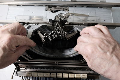 Cropped hands holding typewriter on table