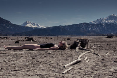 Man lying on mountain against sky