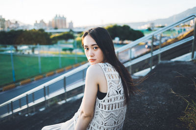 Portrait of beautiful young woman against railing