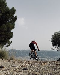 Rear view of man riding bicycle on mountain against sky