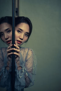 Portrait of young woman by mirror with reflection