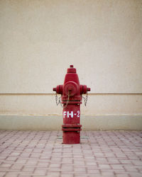 Red fire hydrant on sidewalk against wall