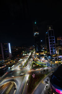 High angle view of illuminated street amidst buildings in city at night