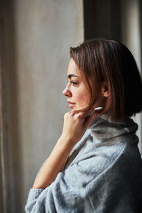 Woman looking through window at home