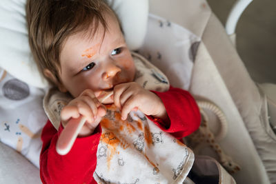 Baby girl licking spoon on bed