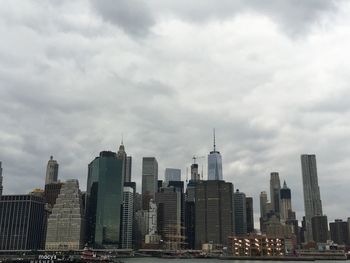 Low angle view of city skyline against cloudy sky
