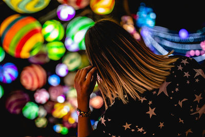 Rear view of woman against illuminated lanterns at night