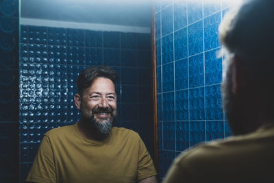 Smiling man looking at mirror in bathroom