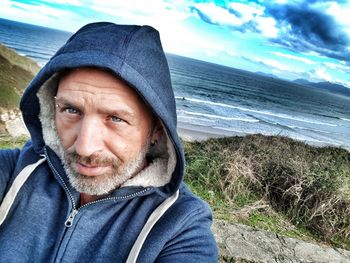 Portrait of man in hooded shirt against sea