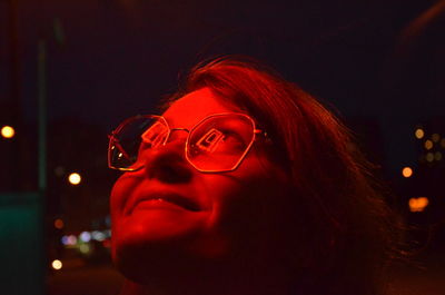 Close-up portrait of young woman with illuminated lighting equipment at night