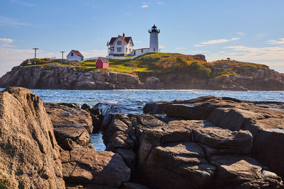 Lighthouse by sea against sky