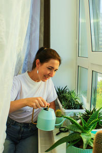 A woman is watering homemade flowers. a home hobby of an adult woman.