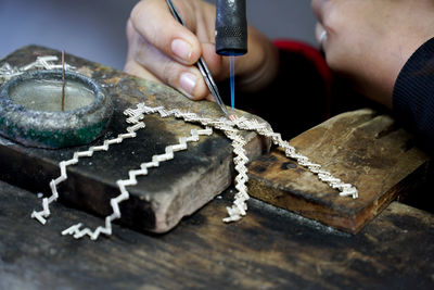 Close-up of person working on silver jewelery