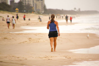 Rear view of woman walking on shore at beach