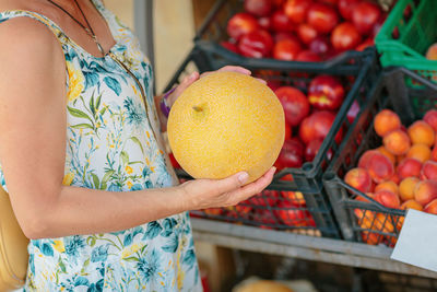 Midsection of woman holding fruits for sale at market