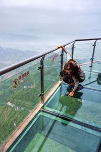 Woman on railing by mountain against sky