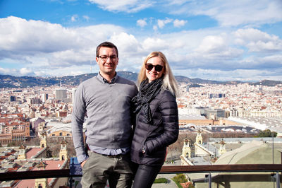 Couple standing on balcony against cityscape