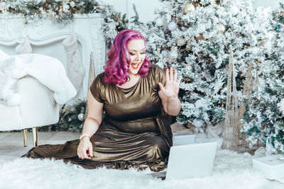 Portrait of young woman using mobile phone while sitting on snow