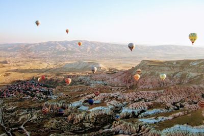 Hot air balloons flying over landscape against sky