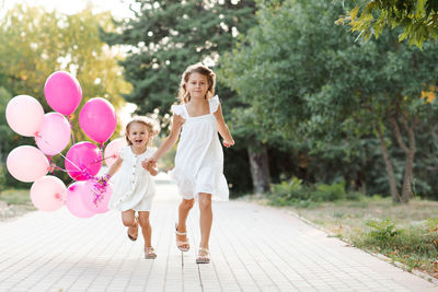 Happy child girls holding balloons running in park outdoor 