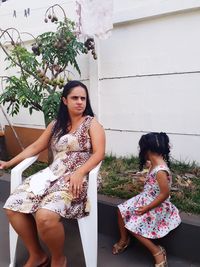 Mother and daughter sitting in yard