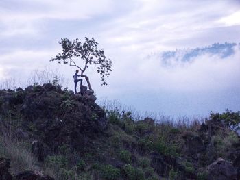 Man standing on mountain against cloudy sky