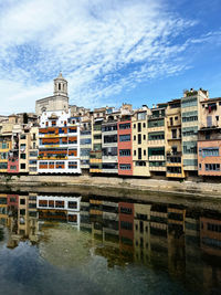 Buildings by river against sky