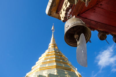 Low angle view of bell hanging at temple against blue sky