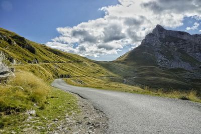 Road leading towards mountains against sky