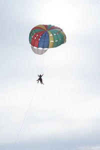 Low angle view of person paragliding against sky