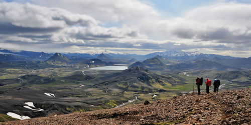 Rear view of people walking on mountain against sky