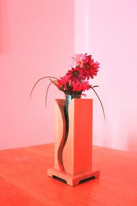 Close-up of red flower vase on table against wall