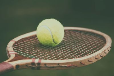 Close-up of tennis ball on racket against green background