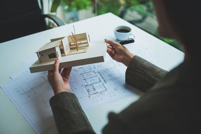 Cropped hand of woman with house model