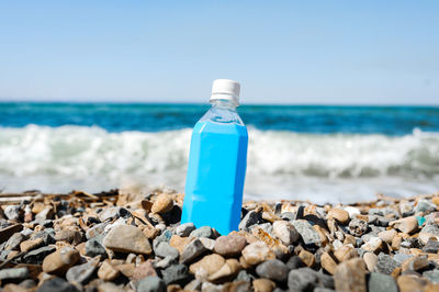 Water bottle on stones at beach against sky