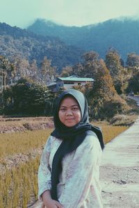 Portrait of smiling young woman standing on land