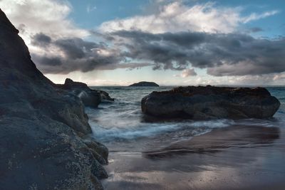 Rock formation on beach against sky