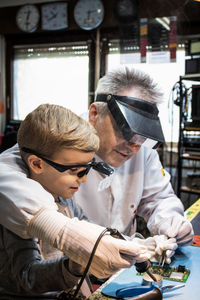 Grandfather and boy repairing computer part on table at home