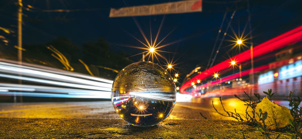 Close-up of light trails on street seen in crystal at night