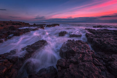 Scenic view of sea against dramatic sky during sunset