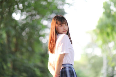 Young woman standing against trees