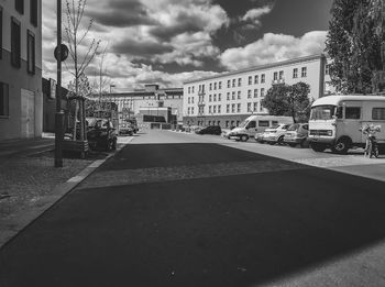 Cars on road by buildings in city against sky