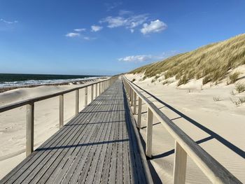 Footbridge over sea against sky