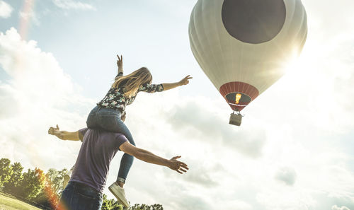 Couple enjoying on field while hot air balloon flying in sky