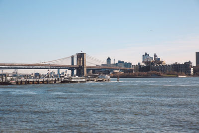 Brooklyn bridge over river against sky