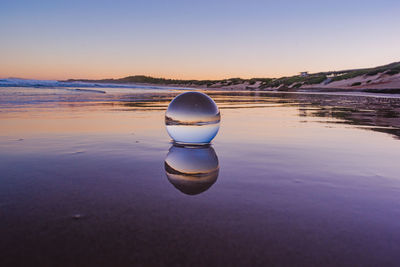 Water on beach by sea against sky during sunset